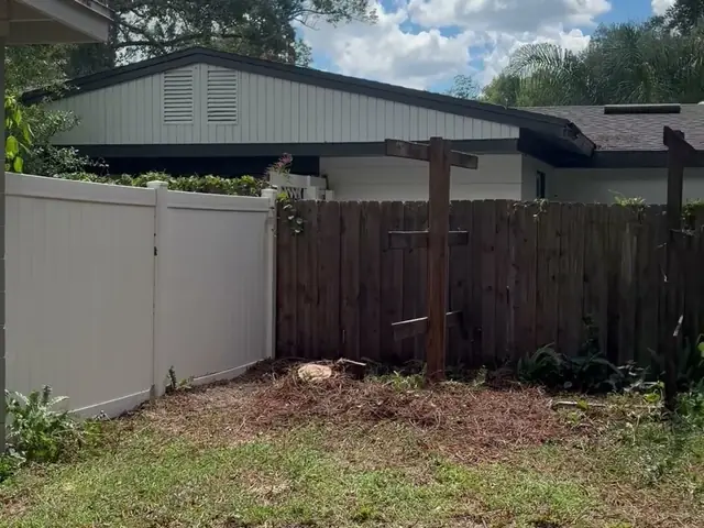 Cleared and raked backyard with both fences and the neighbor's house intact after the removal